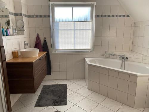 a white bathroom with a tub and a sink at Ferienhaus im Grünen in Lindlar