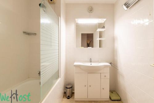 une salle de bain blanche avec un lavabo et une douche dans l'établissement Limousin - proche mer - parking, à La Baule