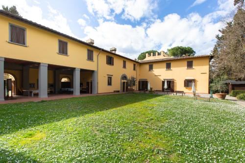 a large yard in front of a yellow building at Poggio Ubertini in Montagnana Val di Pesa