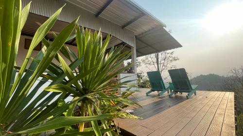 two green chairs sitting on a wooden deck at Monsonkeang Camping view ม่อนสันเกี๋ยง in Mae Chaem