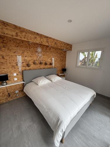 - une chambre avec un grand lit blanc et un mur en bois dans l'établissement Soleil du Sud, à Boisset-et-Gaujac