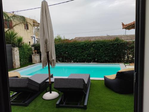 an umbrella and chairs next to a swimming pool at Luxury Villas Chrysa Private Pool & Spa in Nafplio
