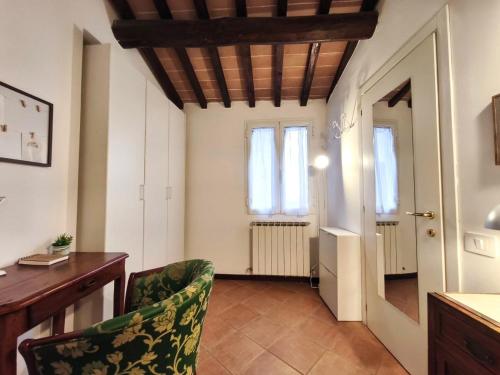 Habitación con silla, escritorio y ventanas. en La Tana del Priore, en Perugia