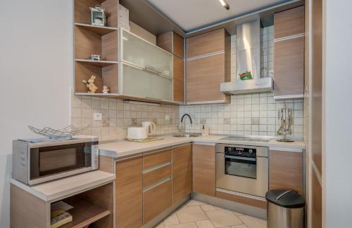 a kitchen with wooden cabinets and stainless steel appliances at Apartment Stiv Luxe in Split