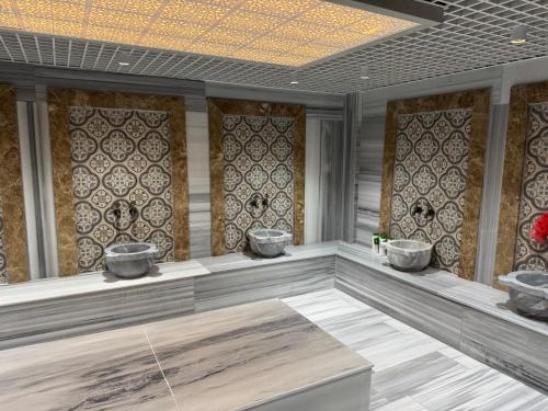 a bathroom with three sinks in a room with tiles at Bademli Han Otel in Ulucak
