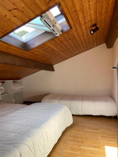 - 2 lits dans une chambre avec une lucarne dans l'établissement Maison au calme à proximité du lac, à Maubuisson