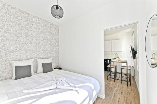 une chambre blanche avec un lit et une table dans l'établissement Convenient apartment near Gare de Lyon, à Paris