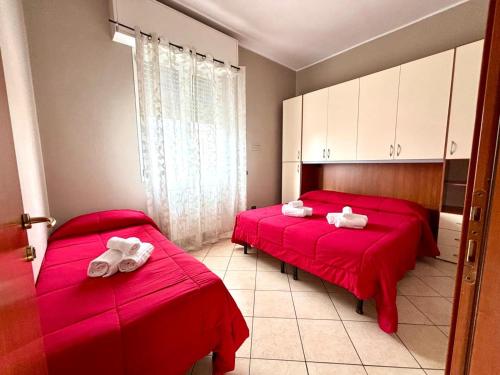 two beds in a room with red sheets and white towels at Residence Oasi Di Monza in Monza