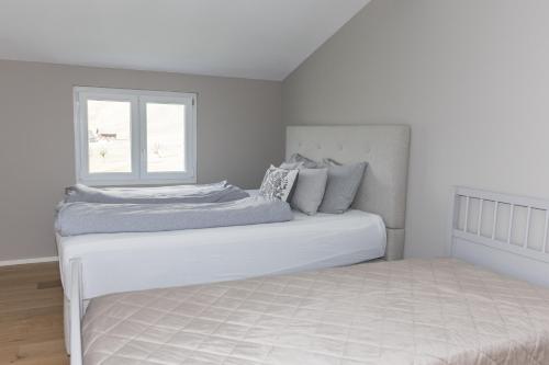 a white bedroom with a bed with a window at LEVA Stay Luzern-Interlaken I Nature I Familie in Sarnen