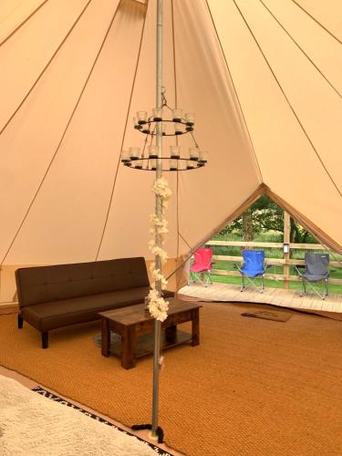 a tent with a couch and a table and chairs at North Lodge Glamping in Carnwath