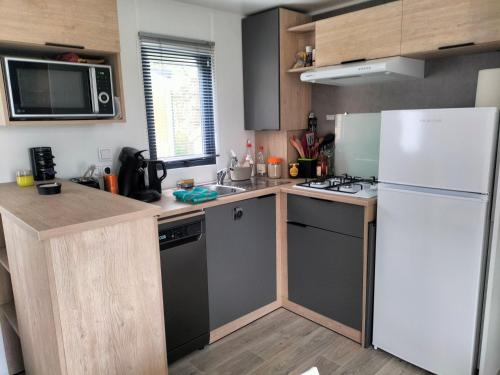 a kitchen with a white refrigerator and a sink at Chalet baie de Canche dans la pinède in Étaples