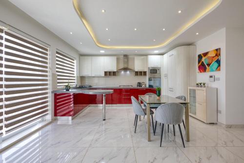 a kitchen with red cabinets and a table and chairs at The Marylou penthouse in Mġarr