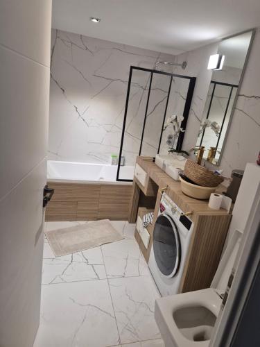 une salle de bain avec un lave-linge et une baignoire dans l'établissement Mimosas résidence, à Juvignac