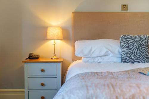 a bedroom with a bed with a lamp on a night stand at Botany Bay Hotel in Broadstairs