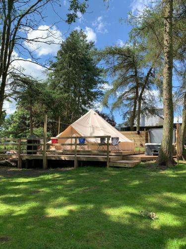 a tan tent on a wooden deck in a yard at North Lodge Glamping in Carnwath