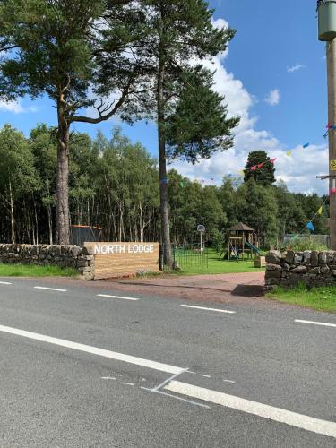 a sign on the side of a road next to a park at North Lodge Glamping in Carnwath