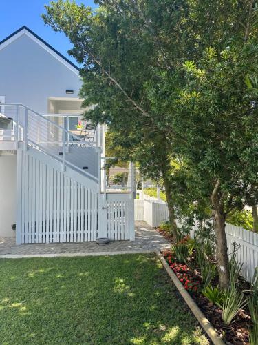 a white fence in front of a yard with a tree at Island Studio Apartment in Knysna