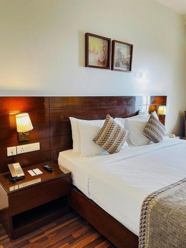 a bedroom with a bed and a phone on a table at Hotel Home In By Amrik Sukhdev in Sonīpat