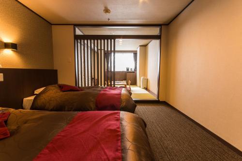 a hotel room with two beds and a large window at Hotel Kanronomori in Niseko