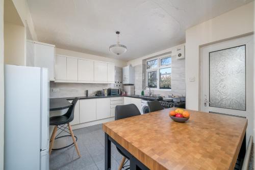 a kitchen with a table with a bowl of fruit on it at Stylish 3 Bed Home with Gardens Fast Transport Links in London