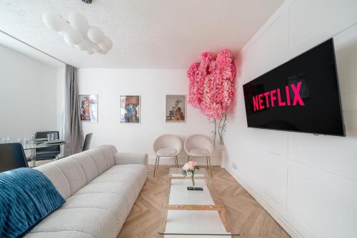 a living room with a couch and a tv on a wall at Stylish 3 Bed Home with Gardens Fast Transport Links in London