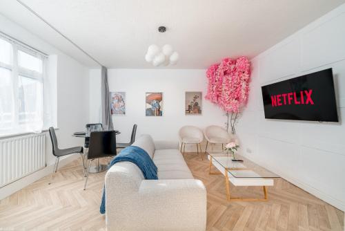 a living room with a white couch and a tv at Stylish 3 Bed Home with Gardens Fast Transport Links in London
