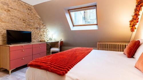 una camera da letto con un letto, una tv e una finestra di La Maison Mercier a Digione
