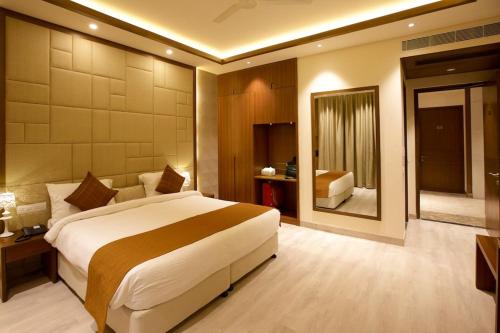 a hotel room with a large bed and a mirror at Ritz Resort Lucknow- The Perfect Blend of Business and Leisure in Lucknow
