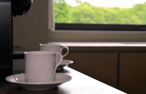 two cups and saucers on a table with a window at Hotel Kanronomori in Niseko