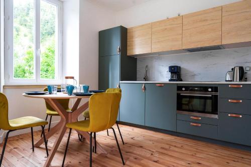 une cuisine avec des placards bleus et une table avec des chaises jaunes dans l'établissement Gîte Col Vert - Ski - Domaine, à Villard-de-Lans