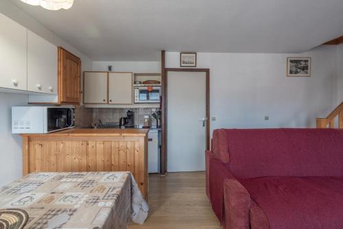 a living room with a red couch and a kitchen at Les Dorines 310 – 6 personnes in Samoëns