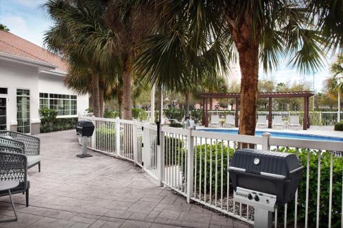 a white fence with palm trees and a swimming pool at Homewood Suites by Hilton Orlando Airport in Orlando