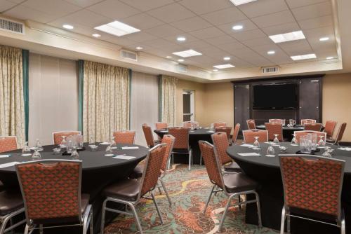 a conference room with tables and chairs and a projection screen at Homewood Suites by Hilton Orlando Airport in Orlando