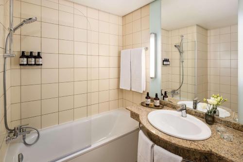 a bathroom with a sink and a bath tub at NH Budapest City in Budapest