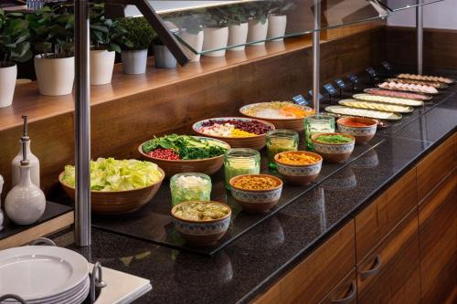 a buffet line with bowls of food on a counter at NH Budapest City in Budapest