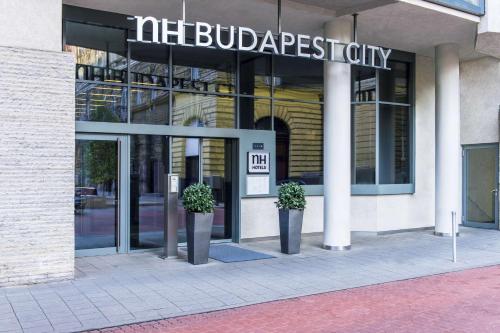 a building with two potted plants in front of it at NH Budapest City in Budapest
