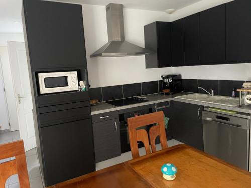 - une cuisine avec des armoires noires et un four micro-ondes blanc dans l'établissement Maison La Rochelle lagord, à Lagord
