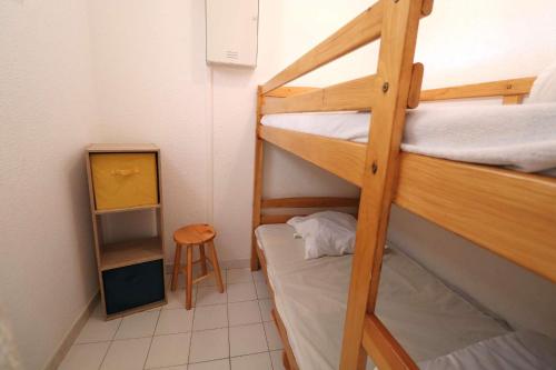 Cette petite chambre comprend 2 lits superposés et un tabouret. dans l'établissement 2 pièces cabine grande terrasse RDC lave-linge parking 400m plage, au Grau-du-Roi