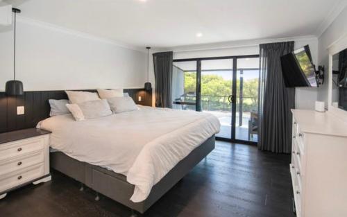 a bedroom with a large bed and a balcony at Huge Luxury Busselton Jetty in Busselton