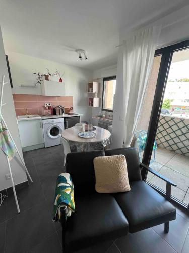 un salon avec un canapé noir et une cuisine dans l'établissement Grand Studio avec Parking et Wifi, à Castelnau-le-Lez