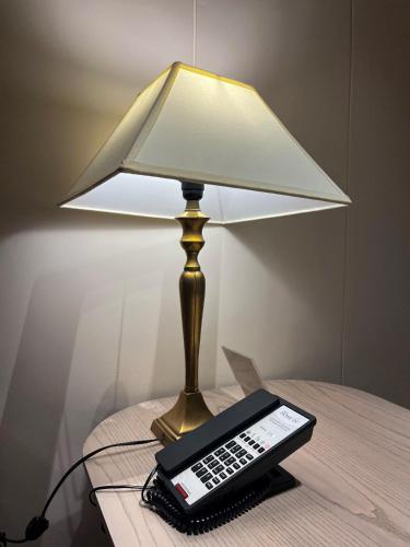 a lamp sitting on a table with a remote control at Hotel Home In By Amrik Sukhdev in Sonīpat