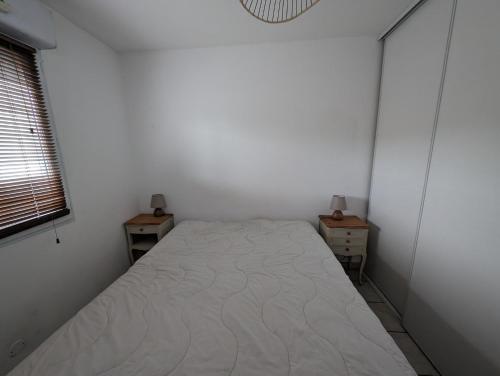 une petite chambre avec un lit et deux tables de nuit dans l'établissement Appartement tout confort Résidence piscine 5 minutes de la plage Mèze, à Mèze