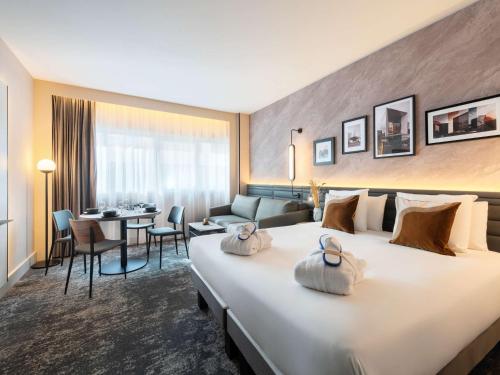 a hotel room with a large bed and a living room at Novotel Paris La Défense Nanterre in Nanterre