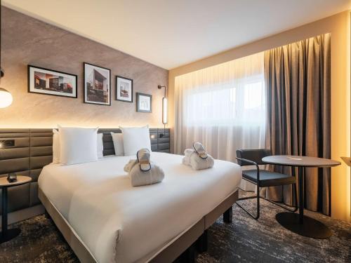 a hotel room with a large bed with towels on it at Novotel Paris La Défense Nanterre in Nanterre