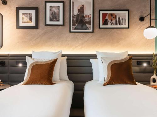 two beds in a hotel room with pictures on the wall at Novotel Paris La Défense Nanterre in Nanterre