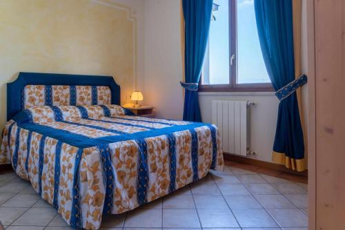 a bedroom with a bed with blue curtains and a window at Appartamento La Quiete in Polpenazze del Garda
