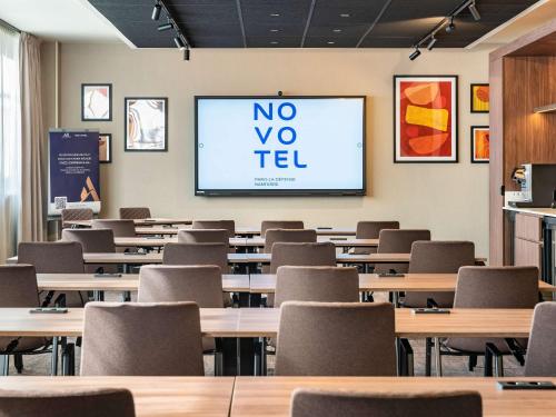 a lecture room with tables and chairs and a screen at Novotel Paris La Défense Nanterre in Nanterre