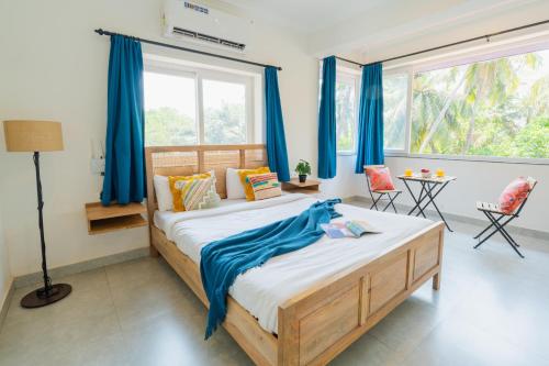 a bedroom with a large bed with blue curtains at Mona Collective at Serenova in Calangute