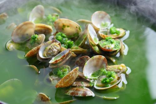 a plate ofcooked clams and broccoli on top of water at KAMENOI HOTEL Kujukuri in Asahi