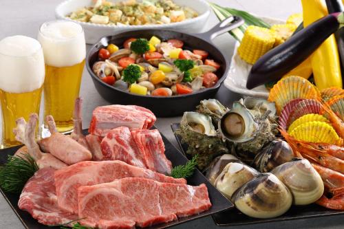 a table topped with seafood and vegetables and a pan of food at KAMENOI HOTEL Kujukuri in Asahi